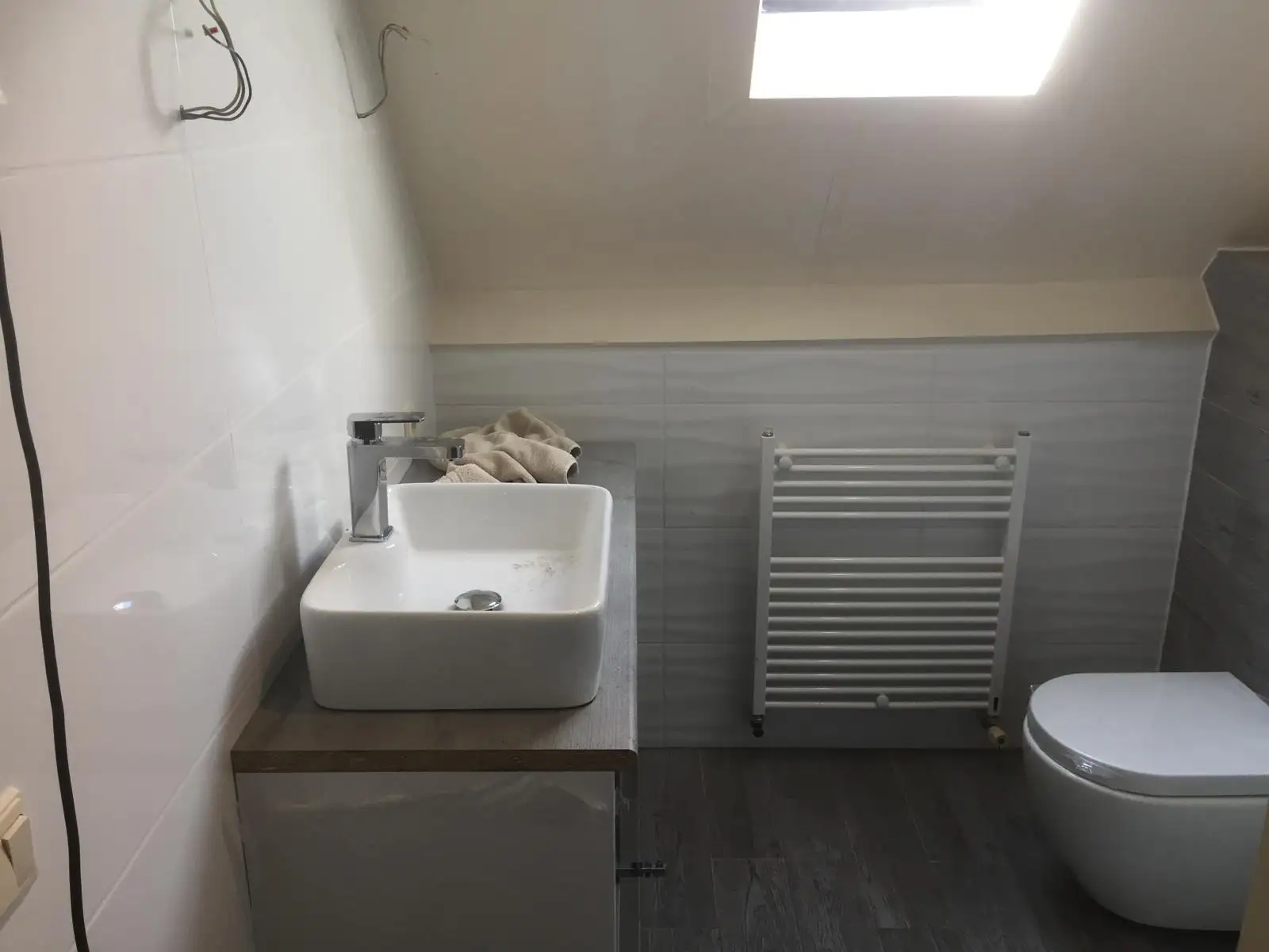 Baño terminado con mueble, radiador toallero y suelo de madera
