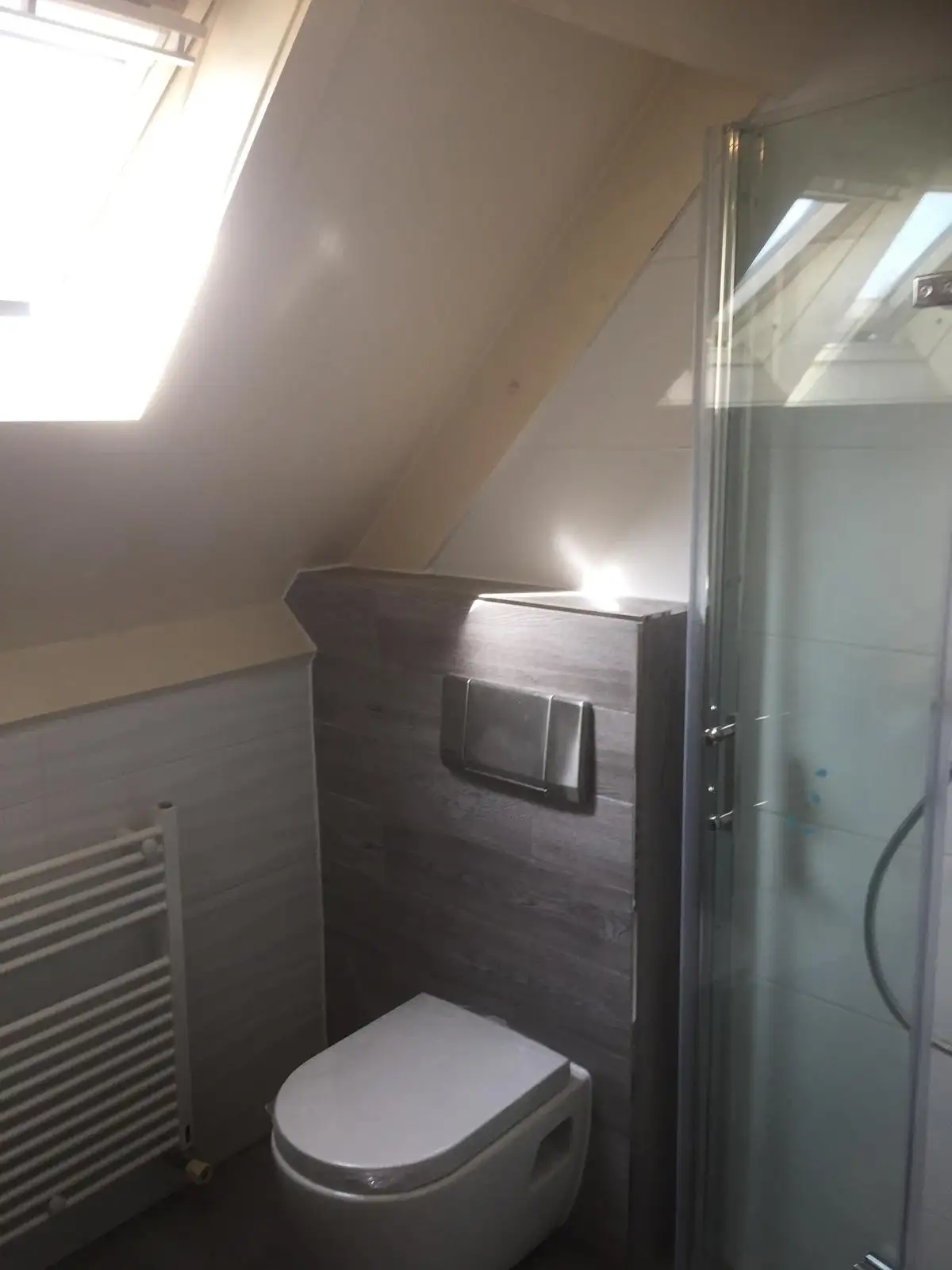 Baño bajo cubierta con ducha y radiador toallero