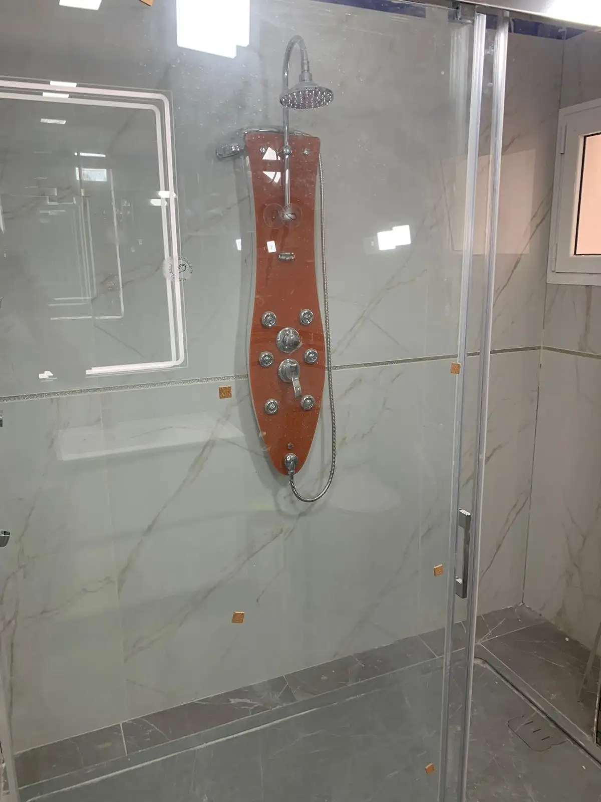 Ducha a ras de suelo con porcelánico efecto mármol y mampara de vidrio